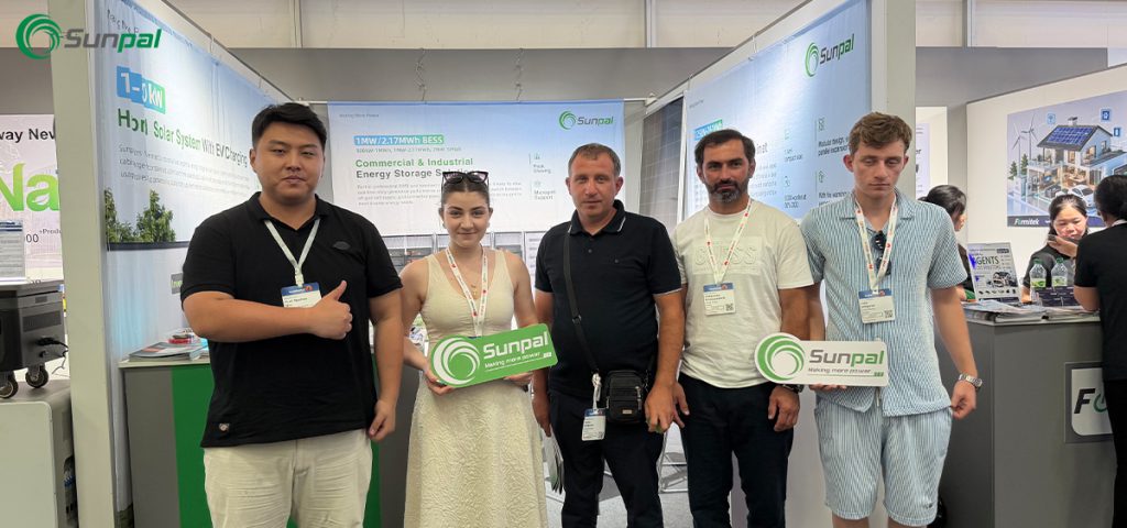 Five representatives hold green and white Sunpal logo signs at a solar tech exhibition booth during The Smarter E Europe 2026.