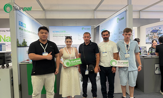 The Sunpal Solar team stands alongside European partners inside their exhibition booth at The Smarter E Europe 2026 event, holding Sunpal-branded signs in front of displays showcasing commercial and residential energy solutions.