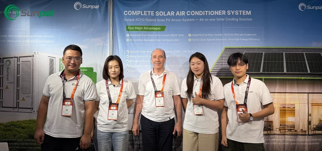 Five Sunpal Solar representatives stand together with a Middle East trade attendee against an event backdrop advertising ACDC hybrid solar cooling technology.
